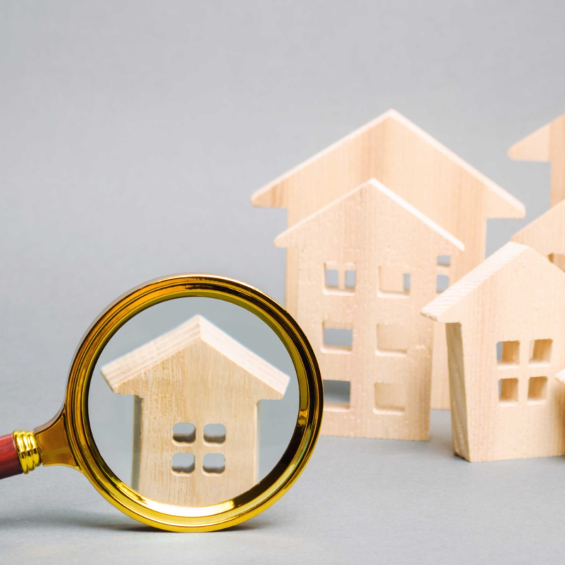 Magnifying glass and wooden houses. House searching concept. Home appraisal. Property valuation. Choice of location for the construction. Search for housing, apartments. Real estate appraiser services